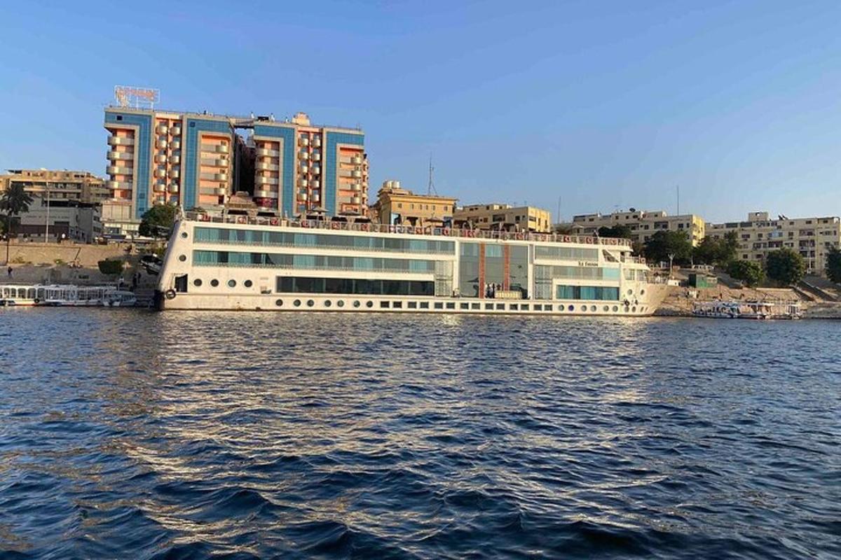 een cruiseschip in het water met gebouwen op de achtergrond