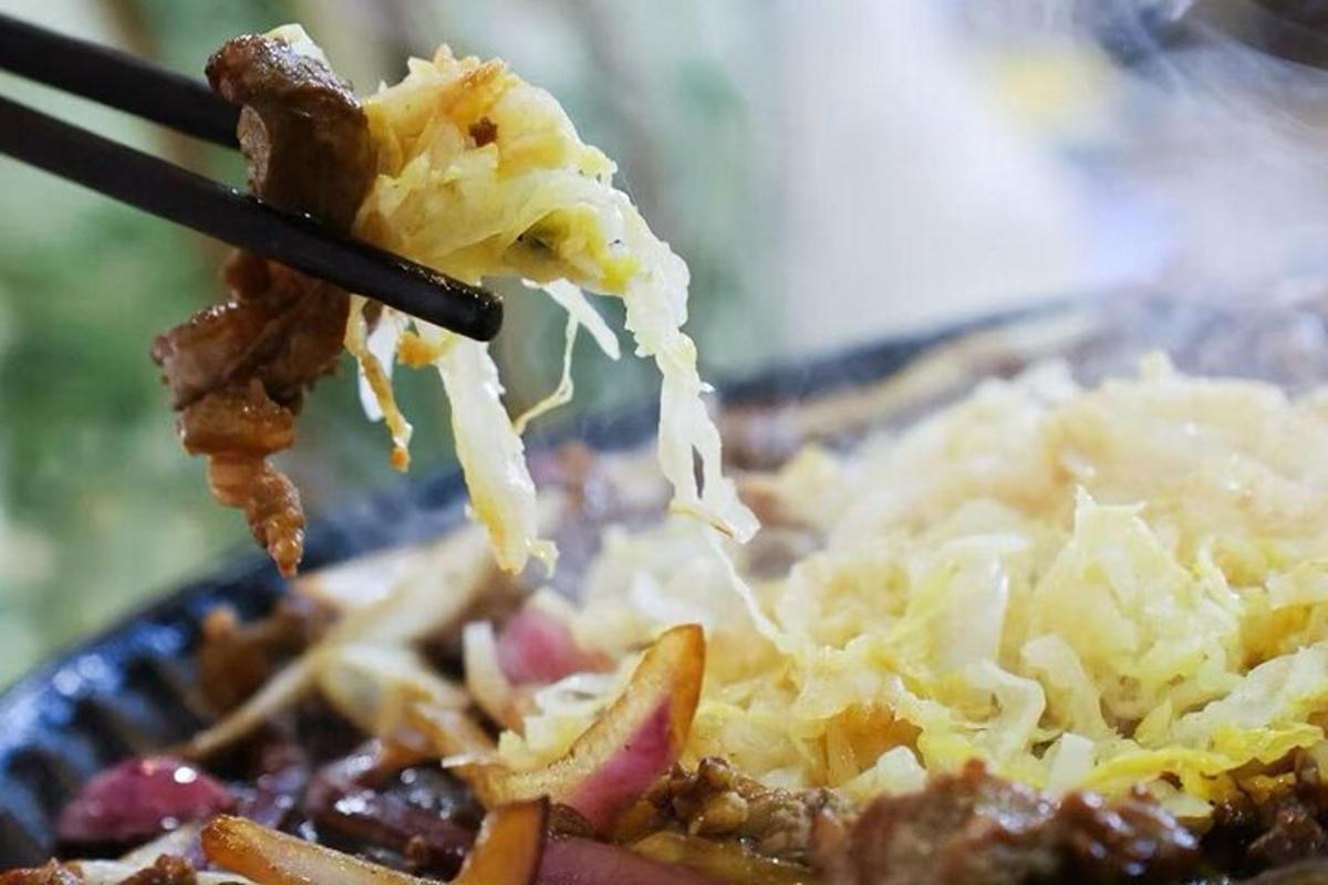 ein Teller mit Essen und Stäbchen, die Essen halten