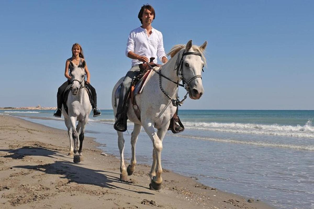 duas pessoas andando a cavalo na praia
