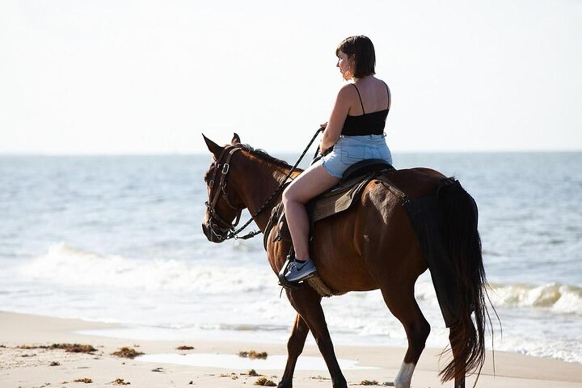 uma mulher cavalgando na praia