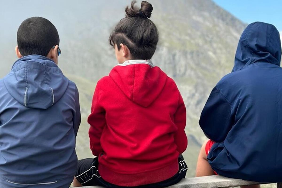 tre persone sedute su una panchina che guardano una montagna