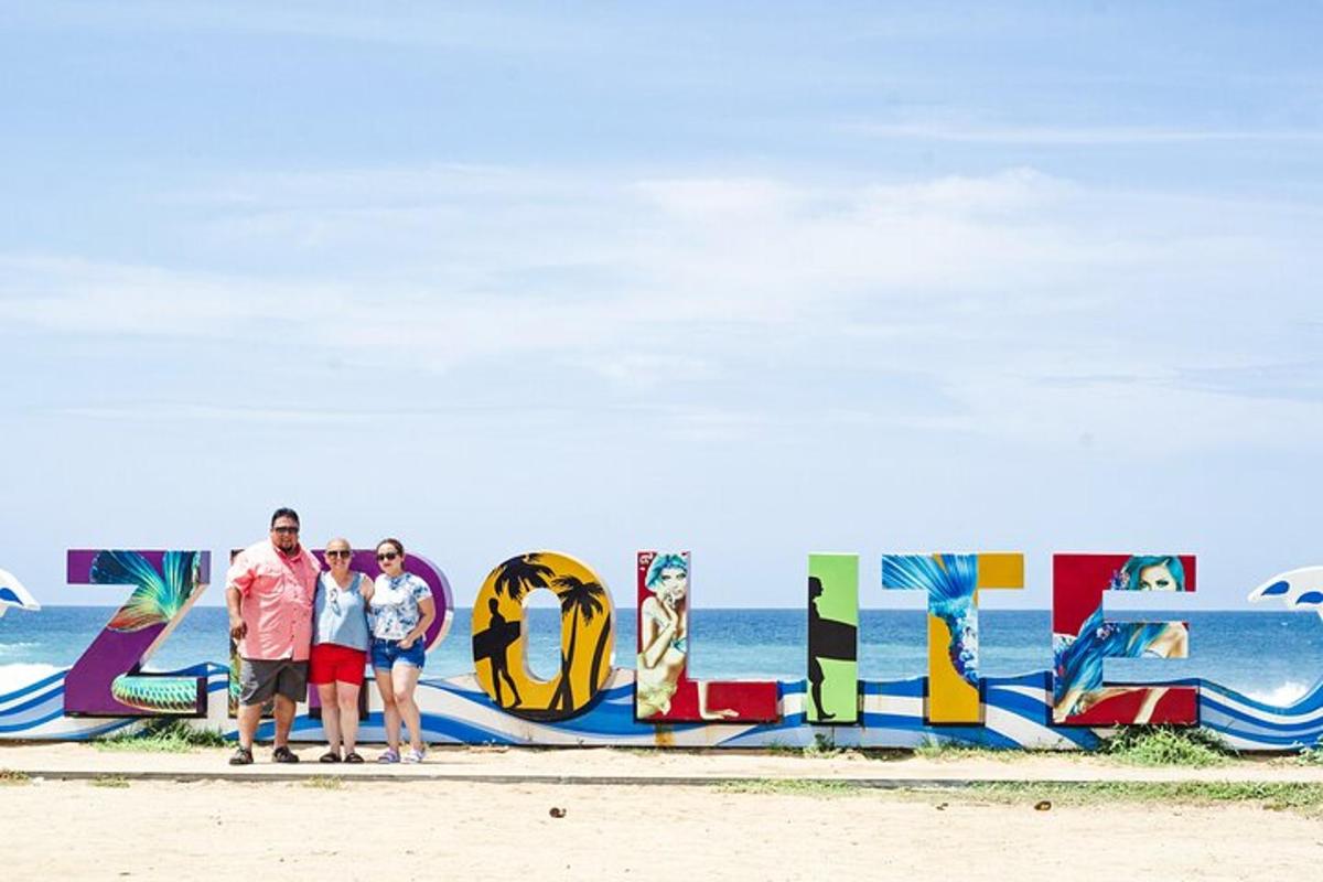 troje ljudi stoje ispred znaka na plaži