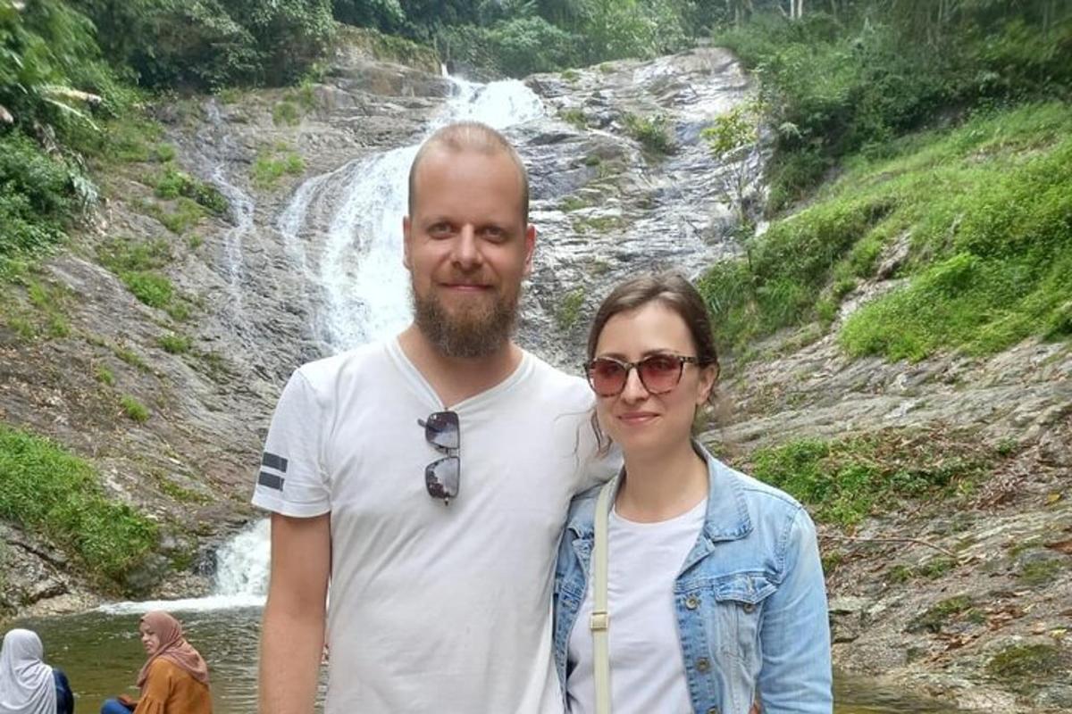 a man and a woman standing in front of a waterfall
