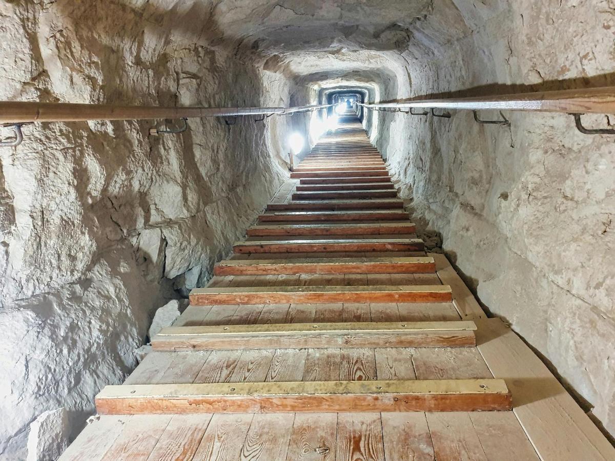 una escala en una cova amb una paret de pedra