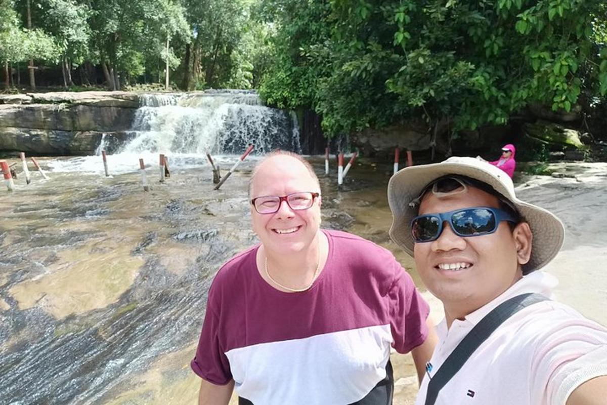 hai người đàn ông đang đứng trước một thác nước