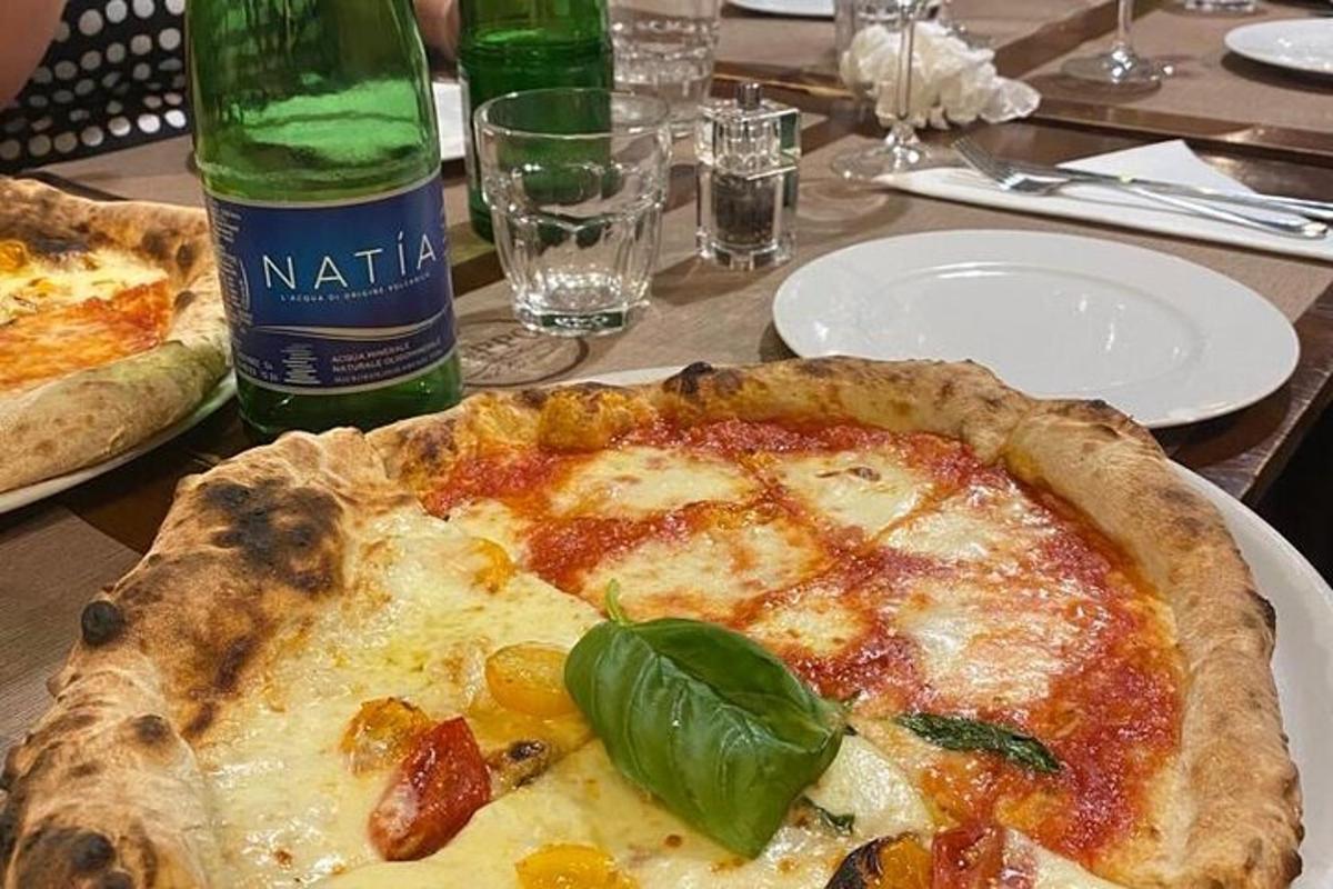 a pizza sitting on a table next to a bottle of wine
