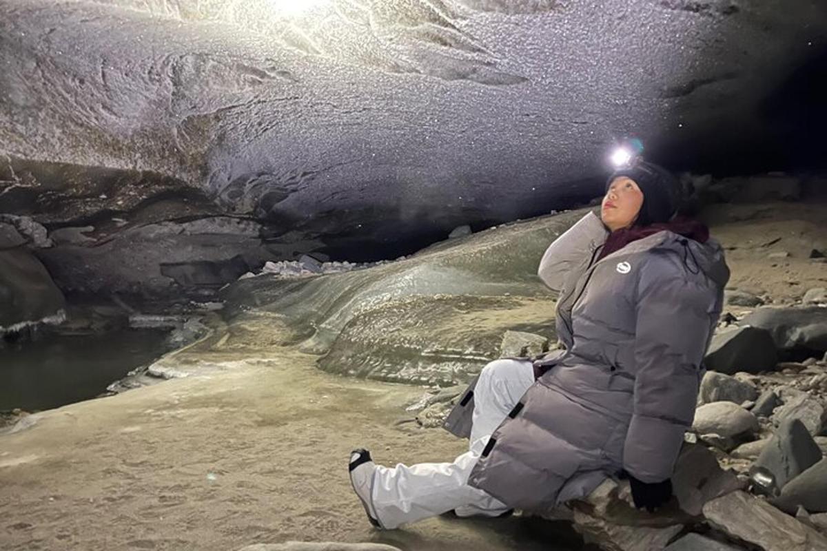 eine Frau, die auf dem Boden neben einer Eishöhle sitzt