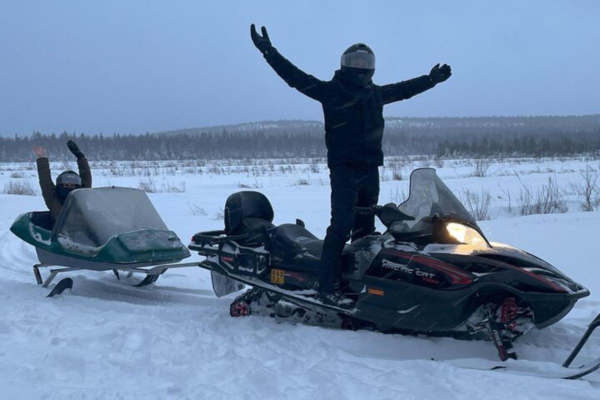 a man standing on a snowmobile with his arms up