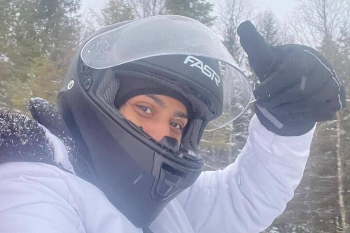 a woman wearing a helmet andraising her hand in the snow