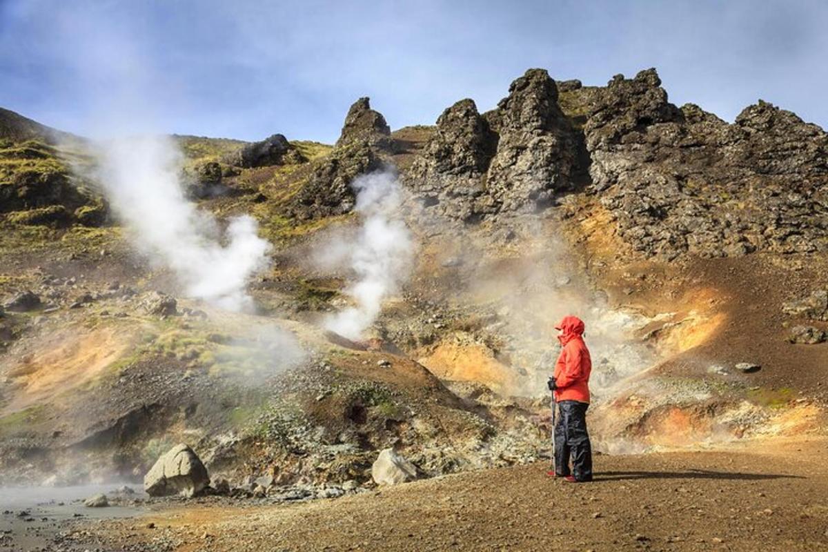 un uomo in piedi davanti a un geyser in una montagna
