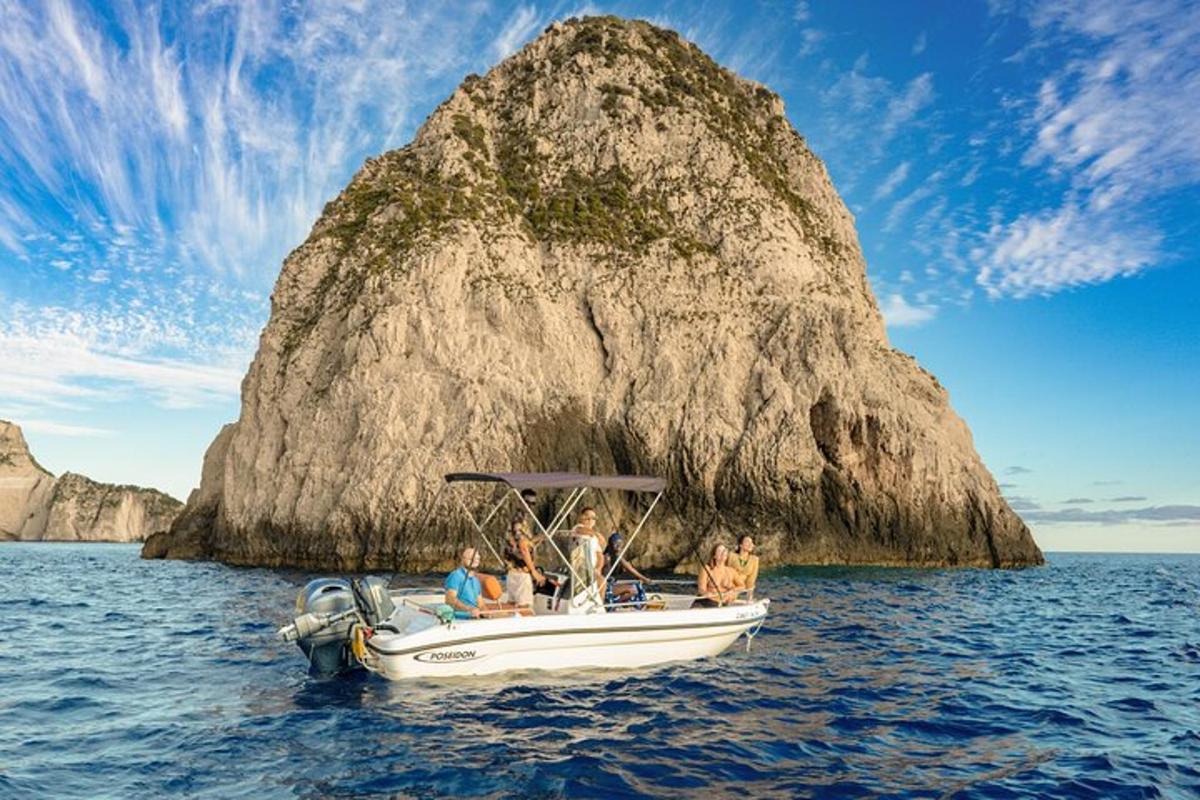 un grup de persones en una barca davant d'una roca