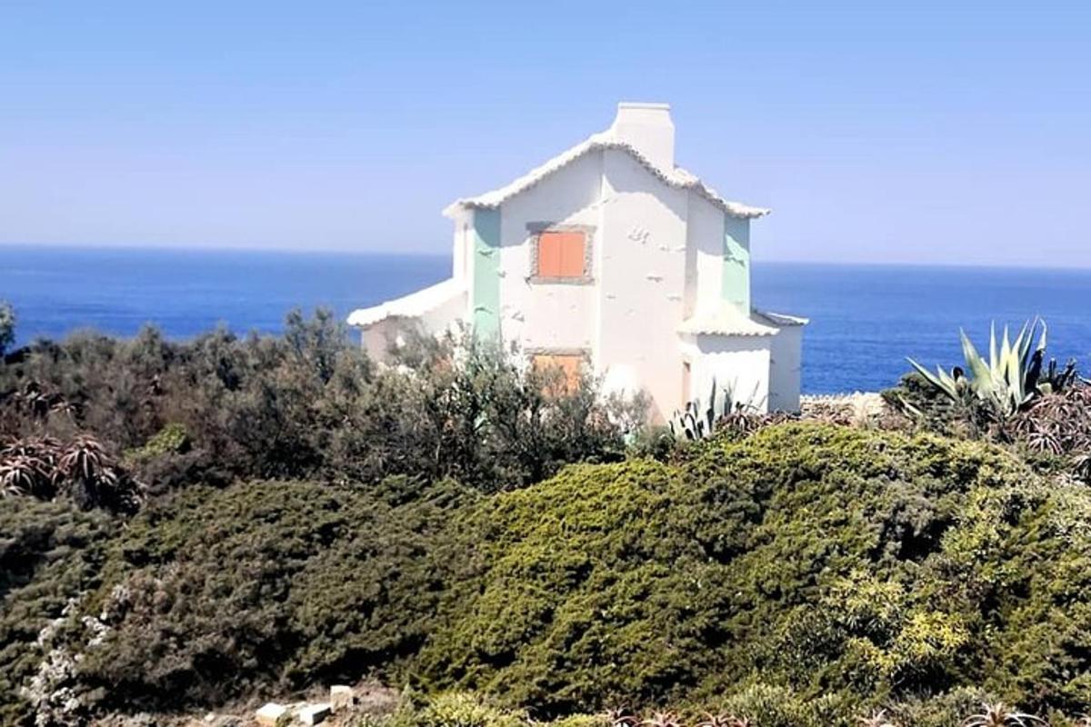 una casa en una colina con el océano al fondo