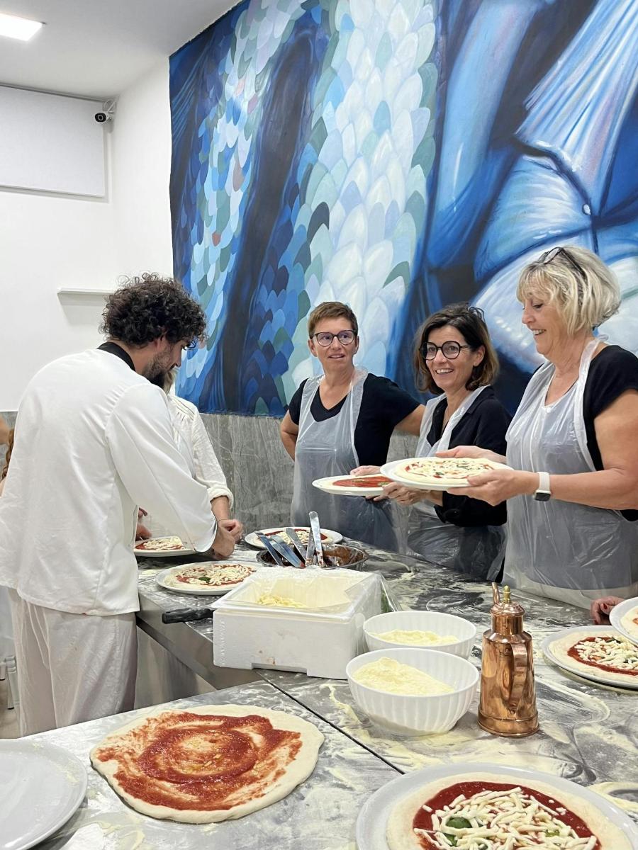 a group of people standing around a table preparing pizza