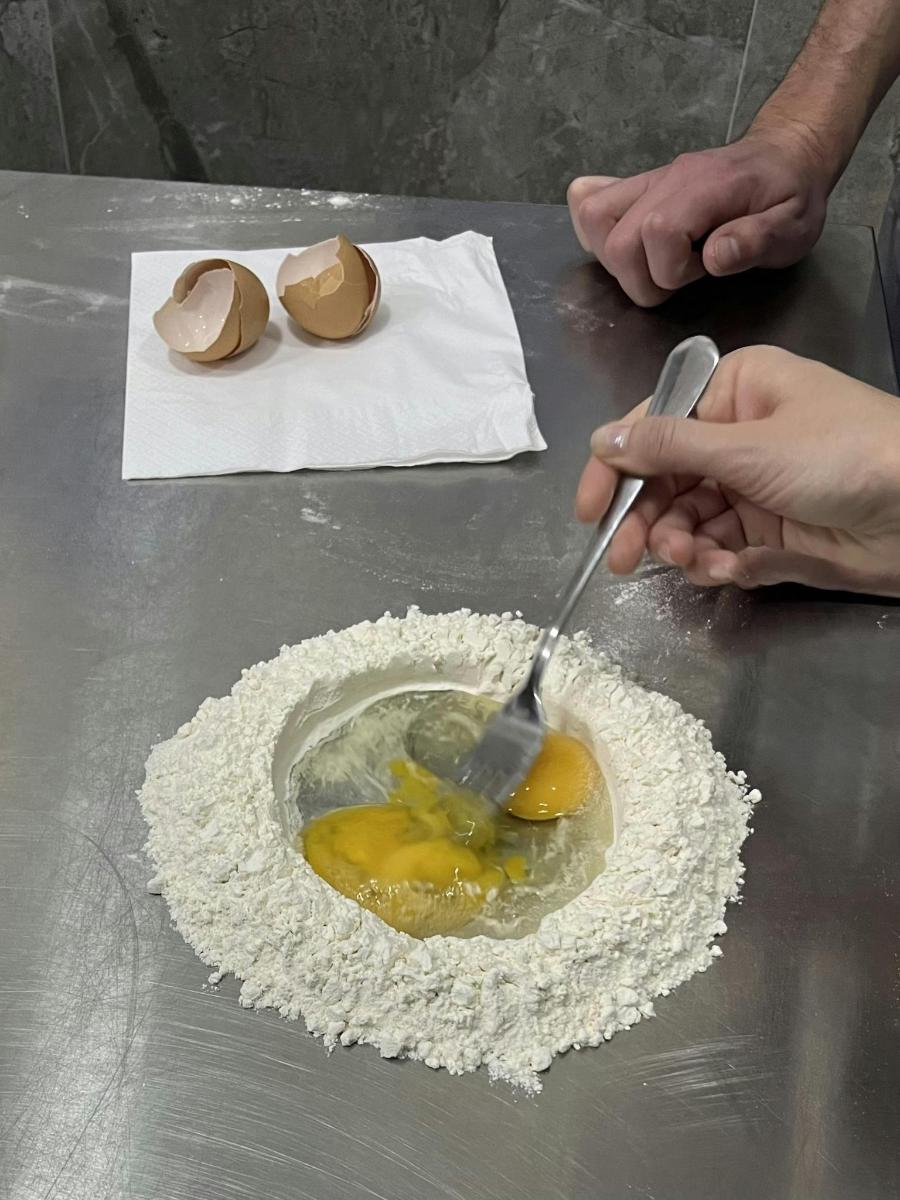 людина, яка змішує яйця в мисці лопаткою