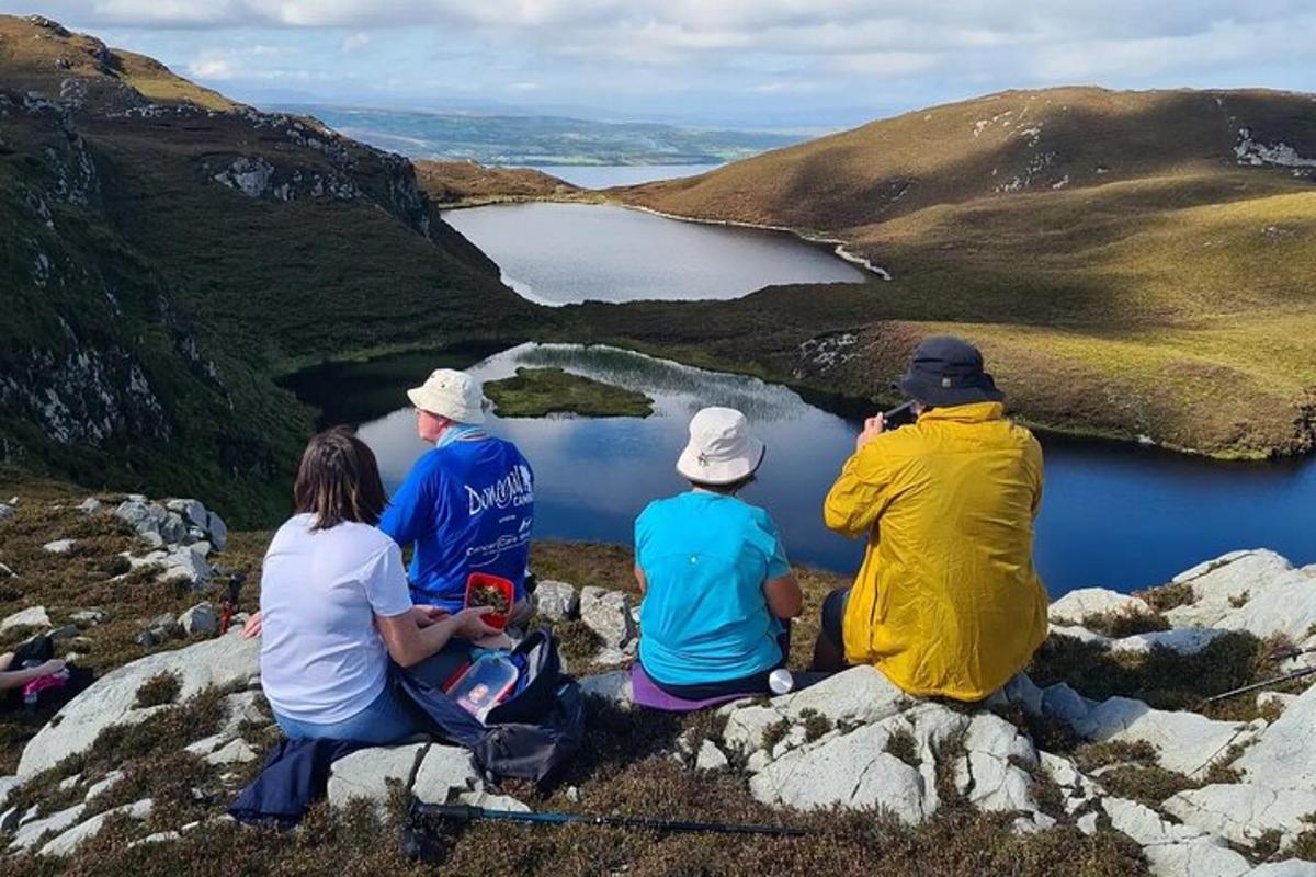 a group of people sitting on a rock overlooking a lake