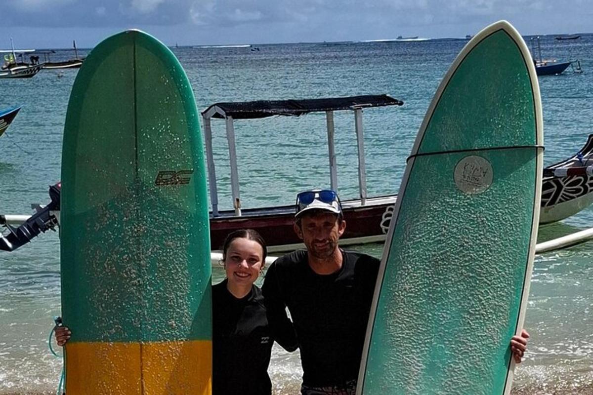 un bărbat și o femeie stând pe plajă cu plăci de surf
