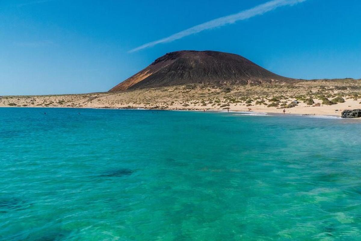 a mountain sitting on top of a beach next to the ocean
