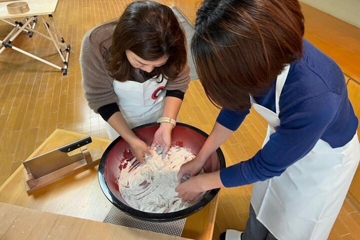 two women are icing a cake on a table