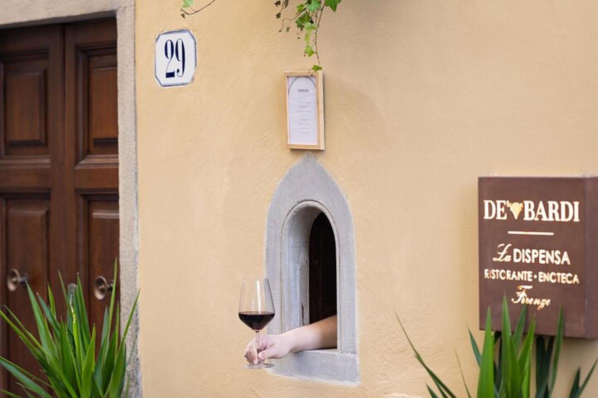 une personne tenant un verre de vin à une fenêtre