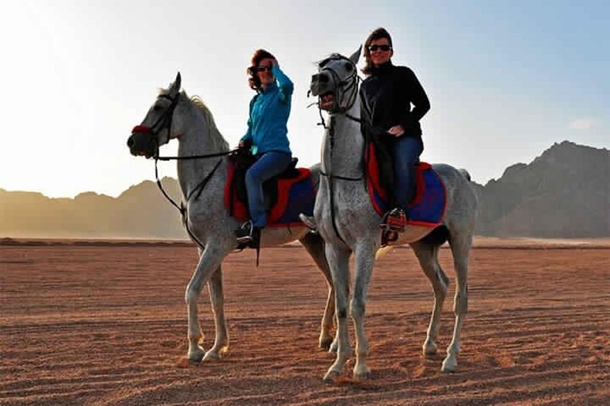 due persone a cavallo nel deserto