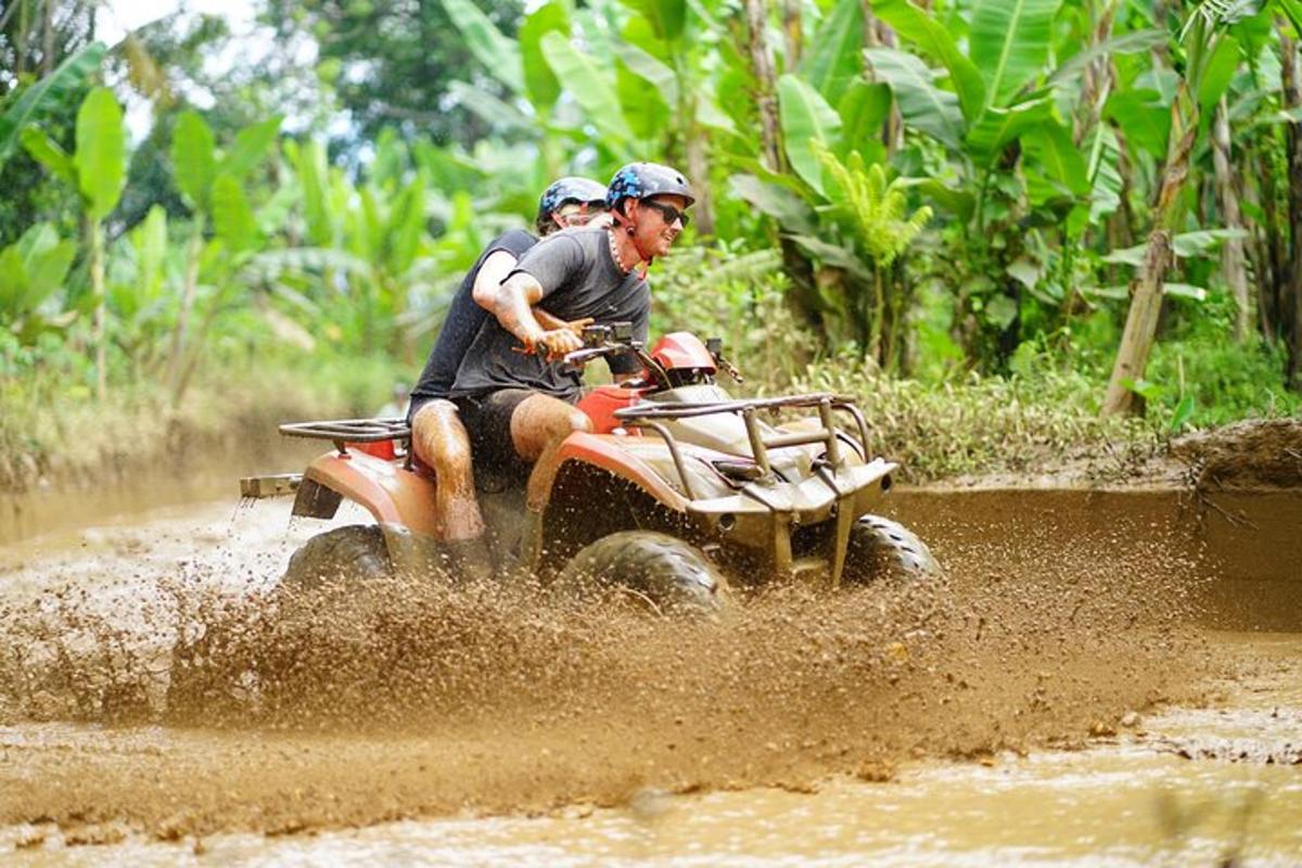 zwei Personen fahren auf einem Quad im Schlamm