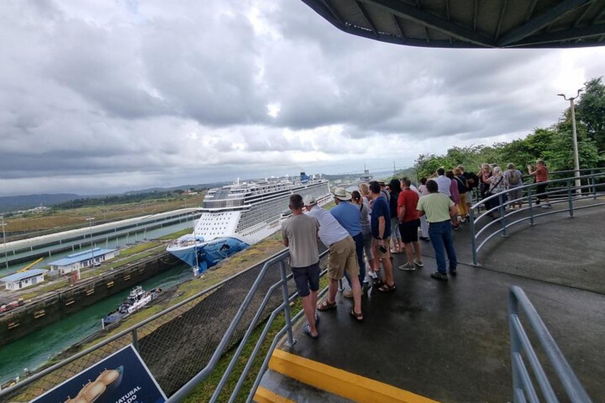 um grupo de pessoas em pé em uma ponte olhando para um navio de cruzeiro