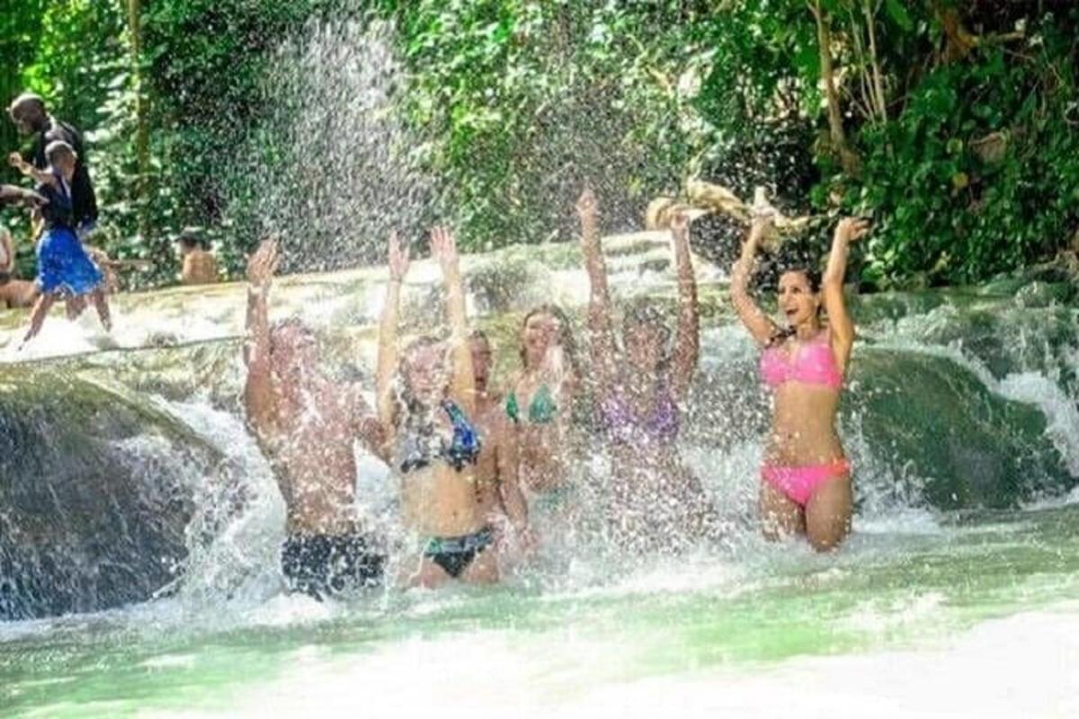 een groep mensen in het water bij een waterval