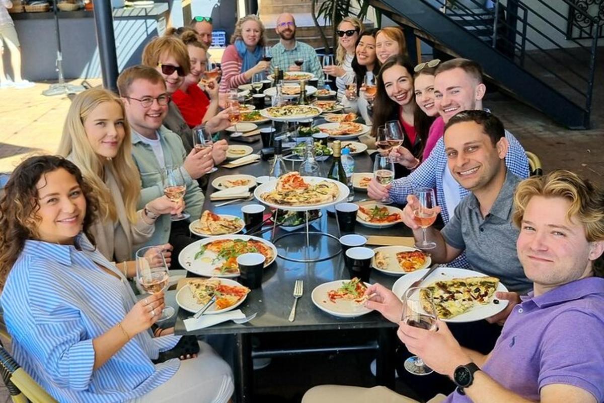 Un grupo de personas sentadas alrededor de una mesa comiendo pizza
