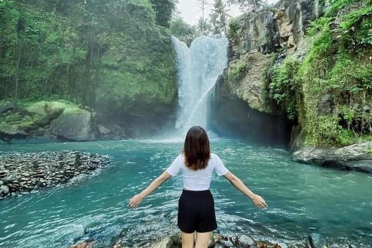 una dona dempeus davant d'una cascada