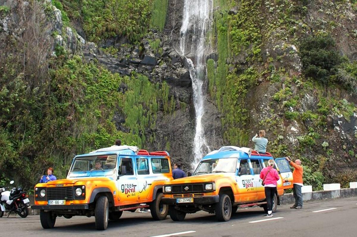 dois caminhões estacionados em uma estrada perto de uma cachoeira