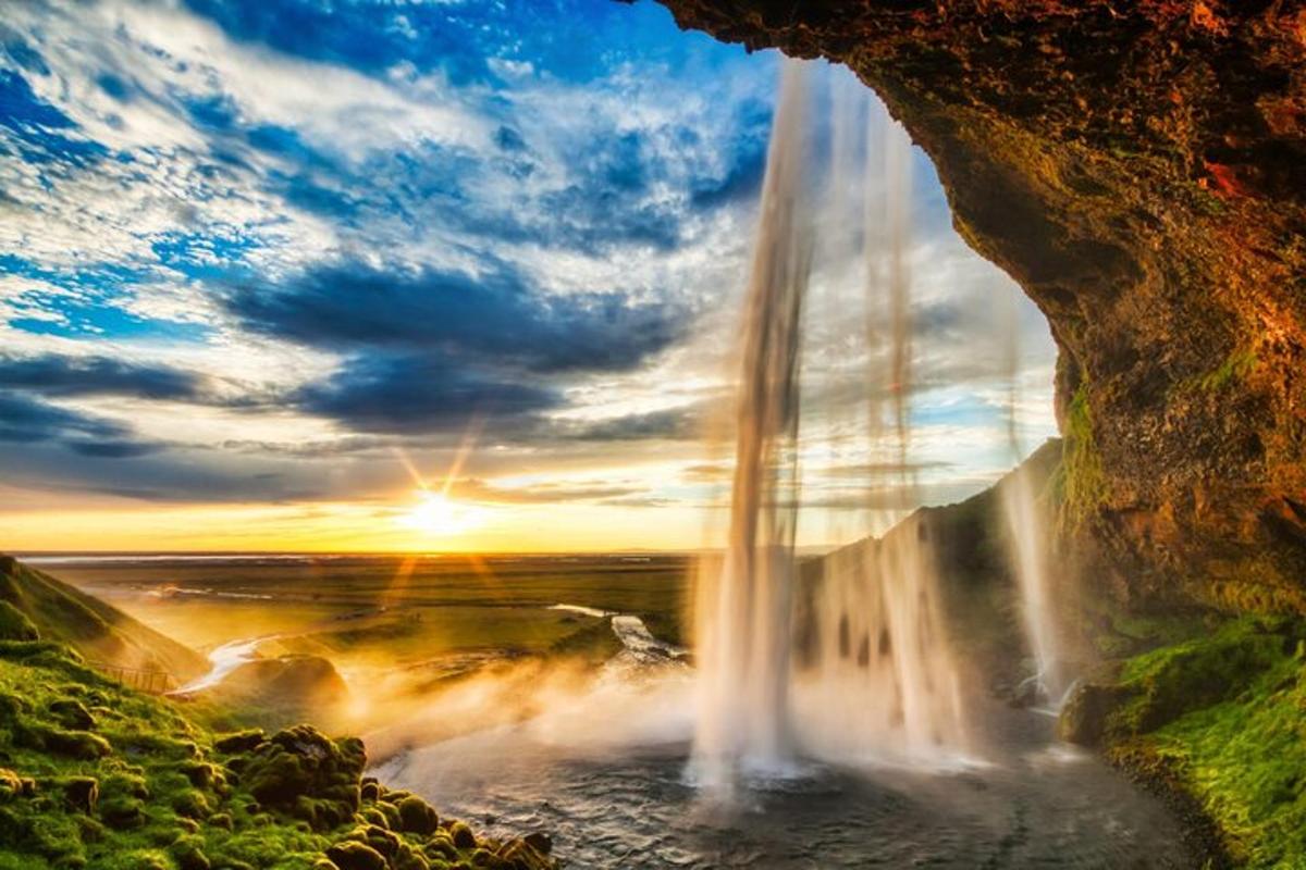 een waterval in een grot met de ondergaande zon erachter