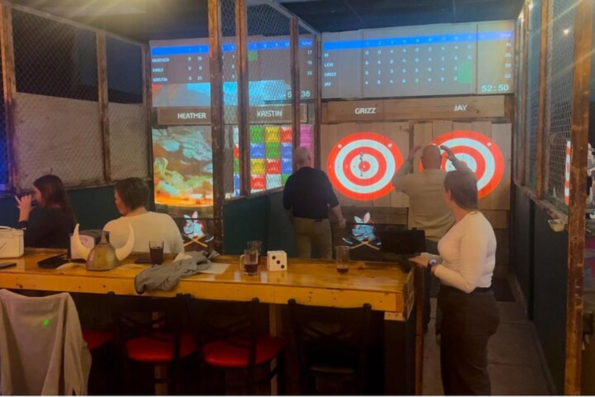 一群人围着桌子站着，手里拿着飞镖