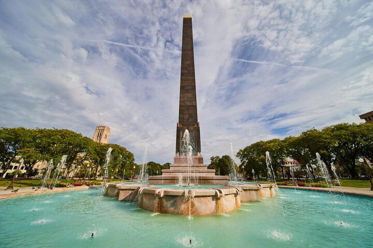 a fountain with a tall obelisk in a park