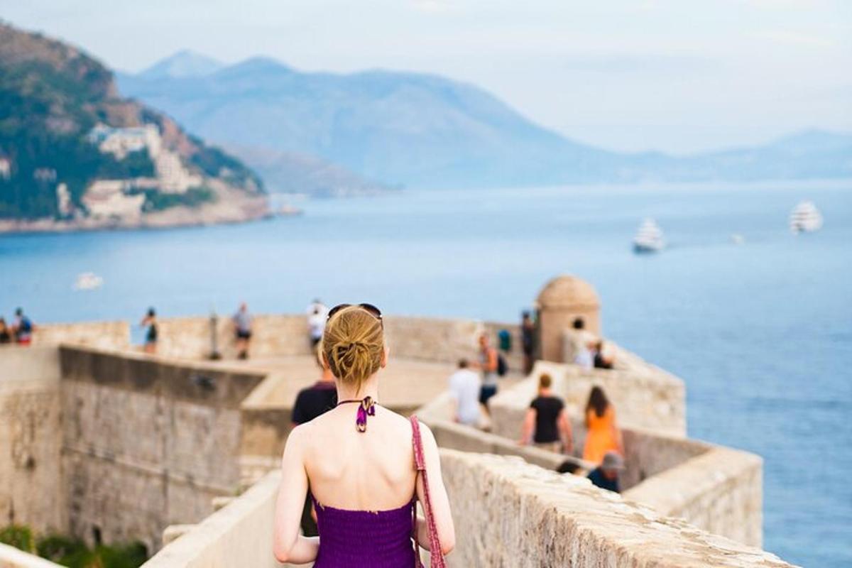 una donna in piedi su un muro che guarda l'acqua