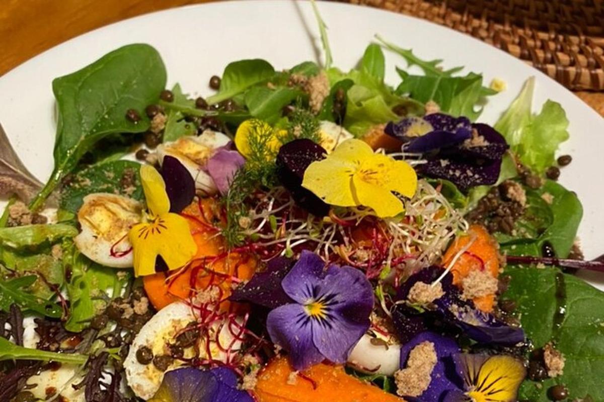 uma salada em um prato branco com flores