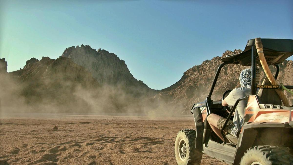 una persona en un jeep conduint pel desert