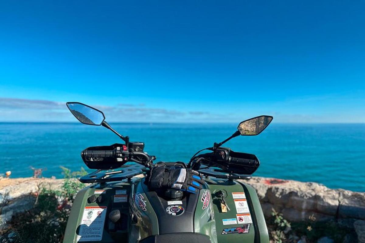 uma scooter verde estacionada em um penhasco com vista para o oceano