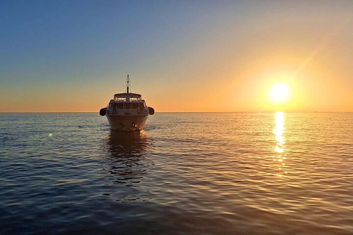 loď plující v oceánu při západu slunce