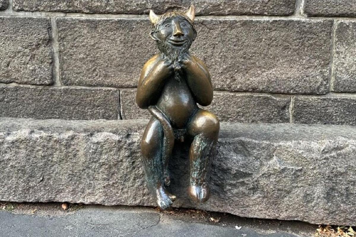 a statue of a little boy sitting on a stone wall