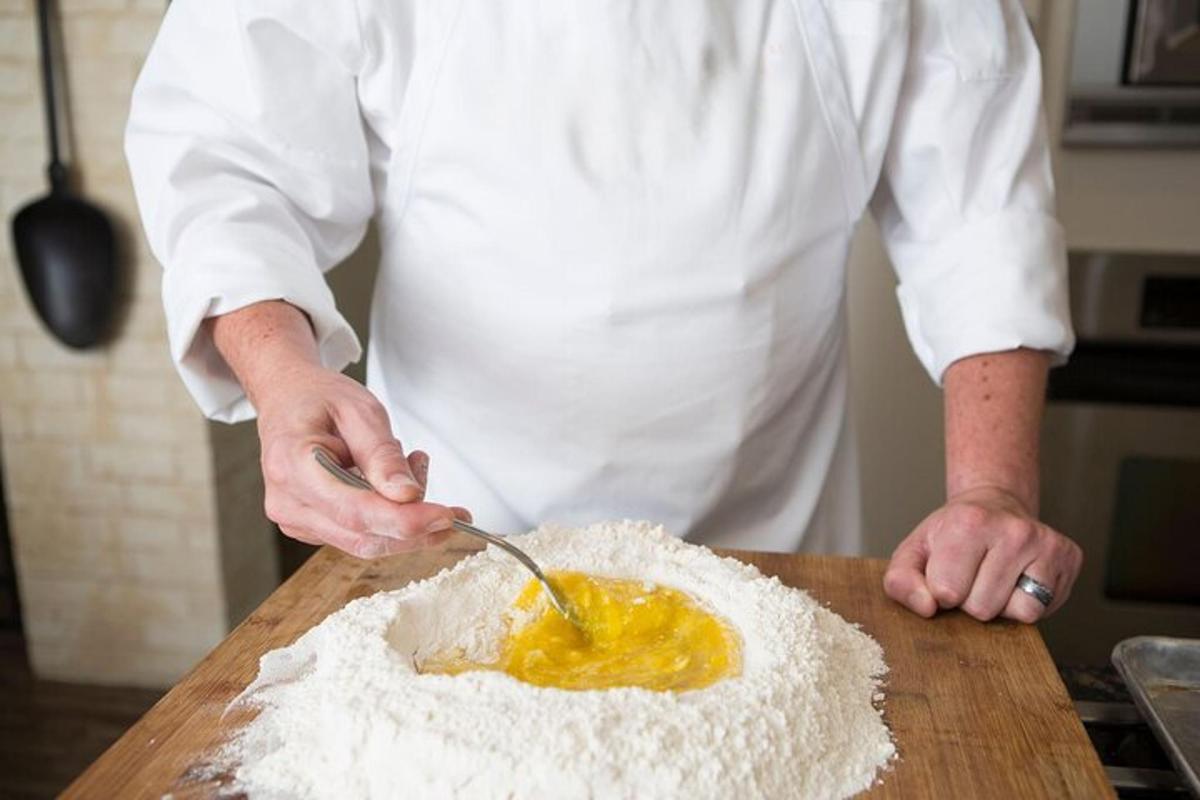 a man in a kitchen preparing food on a table