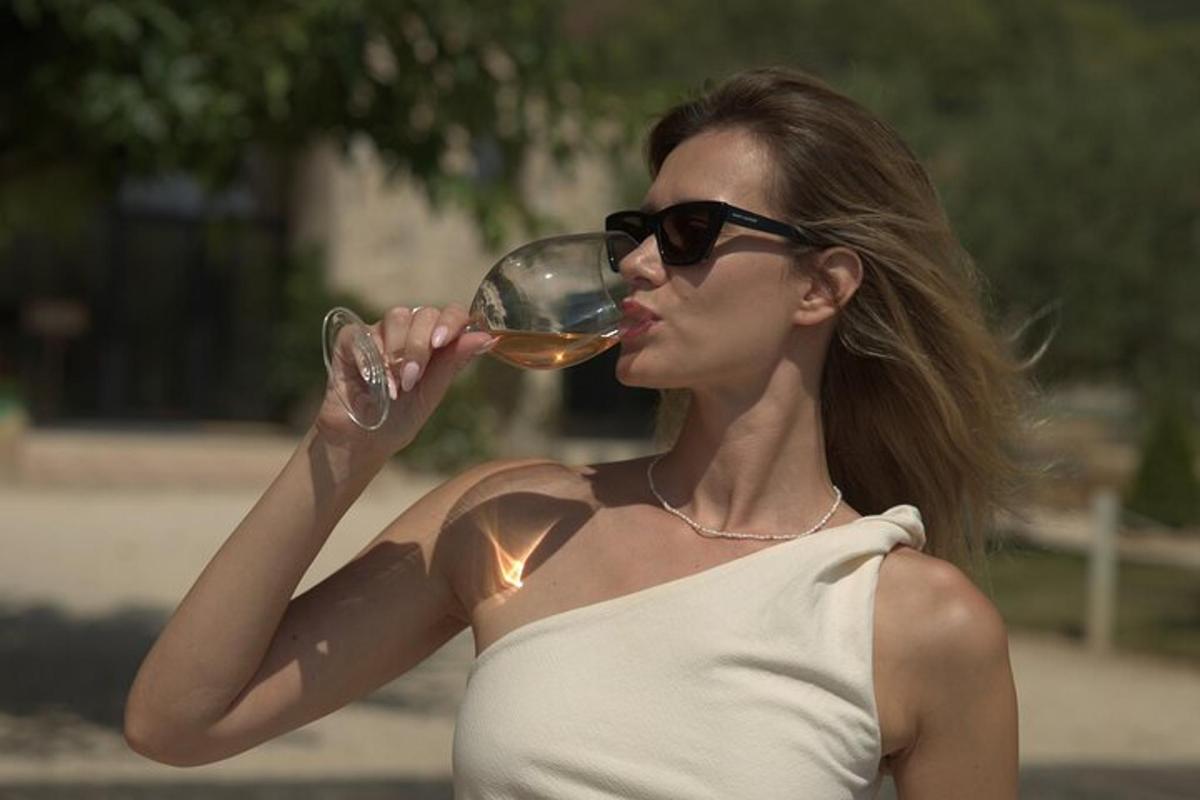 žena ve slunečních brýlích pije sklenici vína