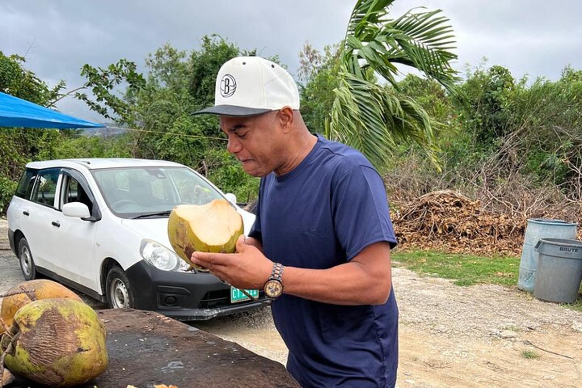 Un hombre sostiene un coco delante de un coche.