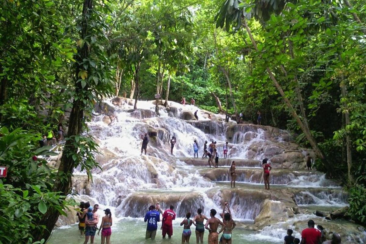 sekumpulan orang berdiri di dalam air di air terjun