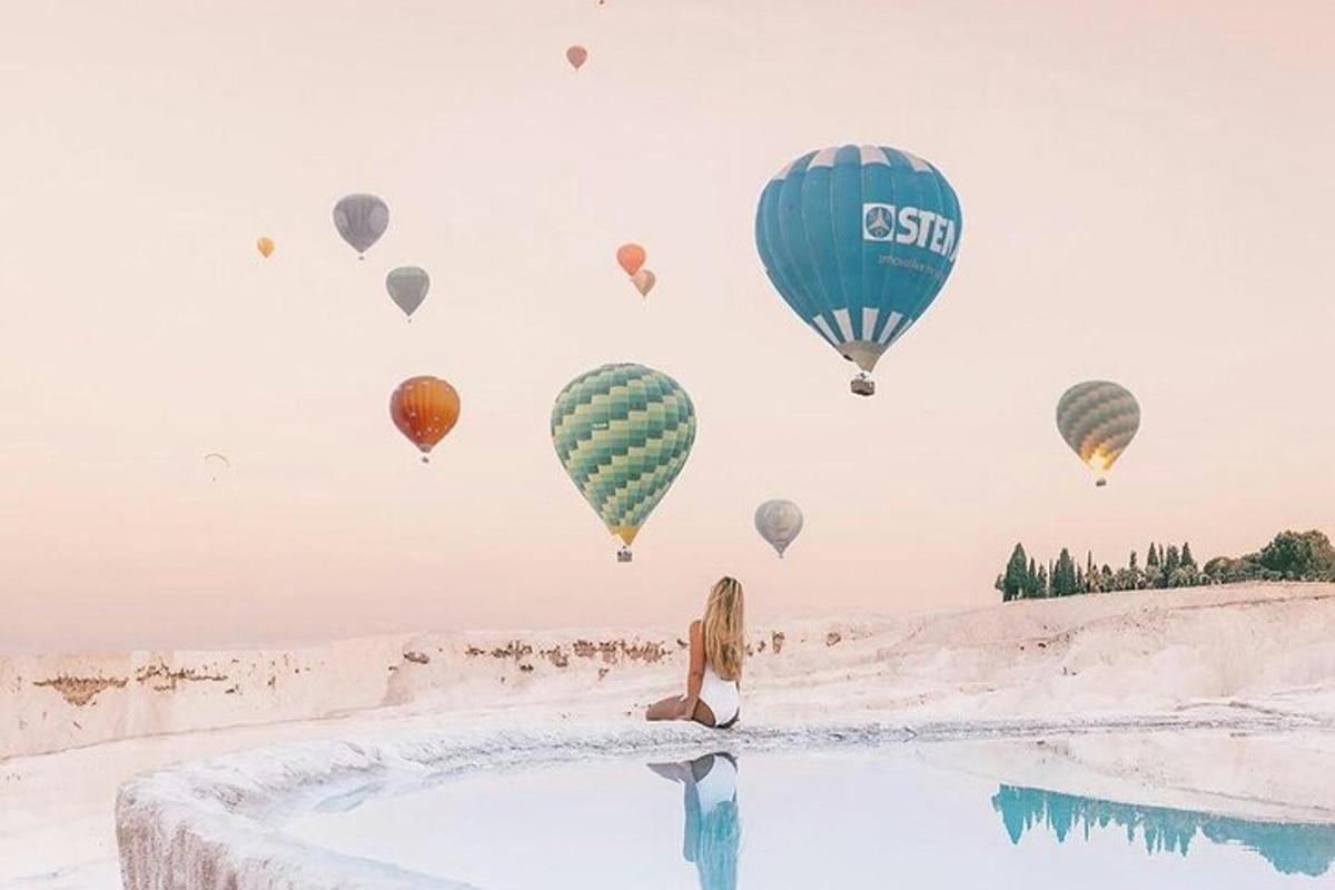 a woman sitting in a pool of water with hot air balloons