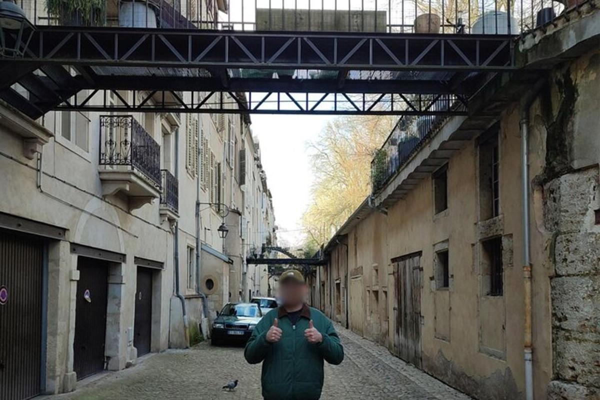 a man walking down an alley with a bridge above him