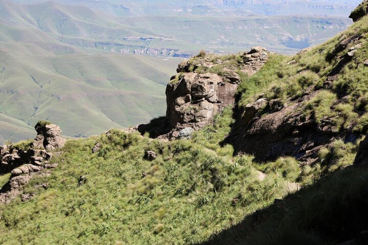 Una vista de una montaña con césped y rocas.