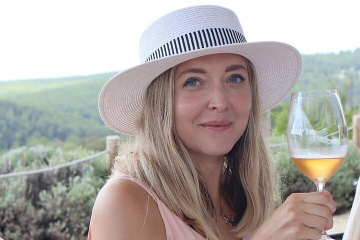 Una mujer con sombrero sosteniendo una copa de vino.