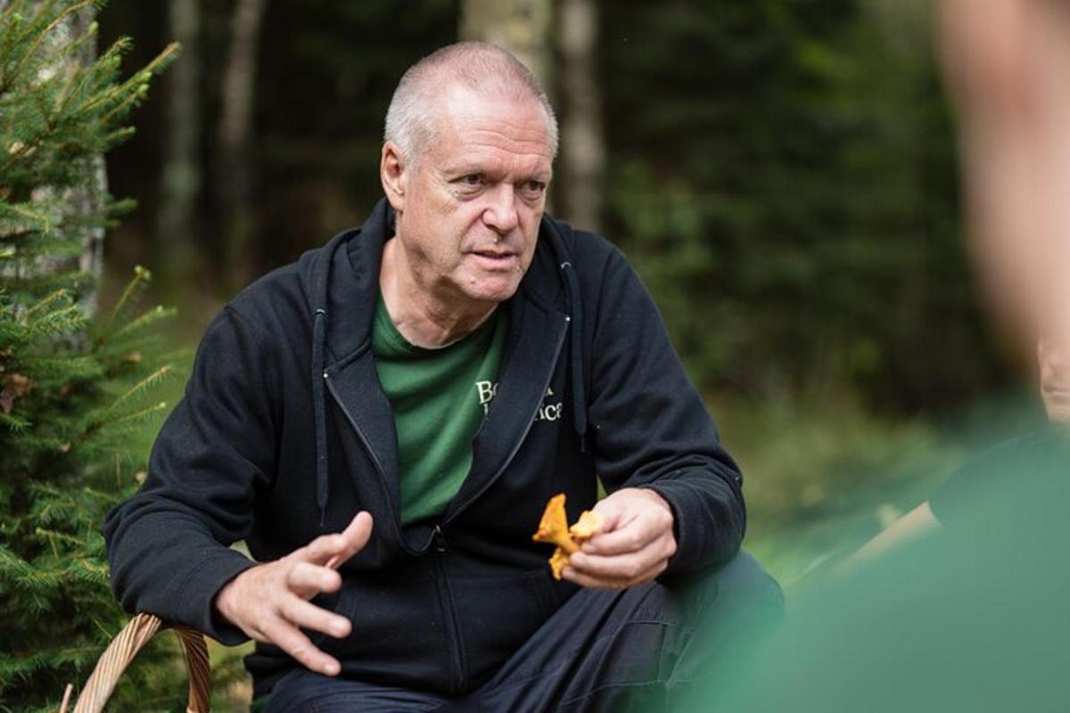 an older man sitting on a chair holding a leaf