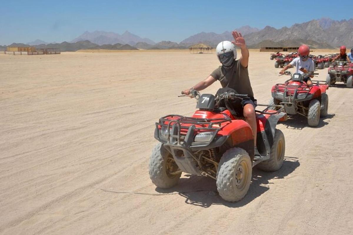 seorang lelaki melambai sambil menunggang atv di padang pasir