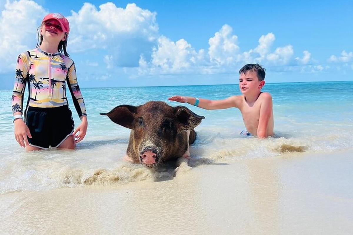 two children standing on a beach with a cow in the water